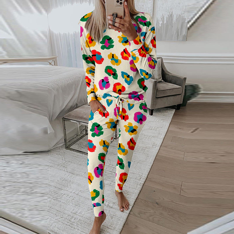 Frau in buntem Blumen-Pyjama macht Selfie im modernen Schlafzimmer. Bequeme Nachtwäsche, stilvolles Design, gemütliche Einrichtung.