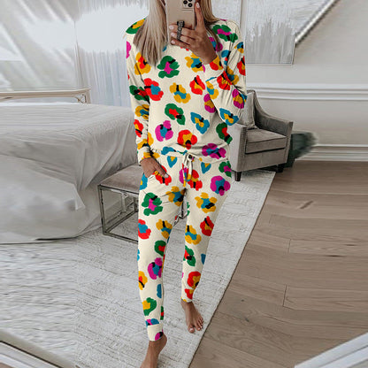 Frau in buntem Blumen-Pyjama macht Selfie im modernen Schlafzimmer. Bequeme Nachtwäsche, stilvolles Design, gemütliche Einrichtung.