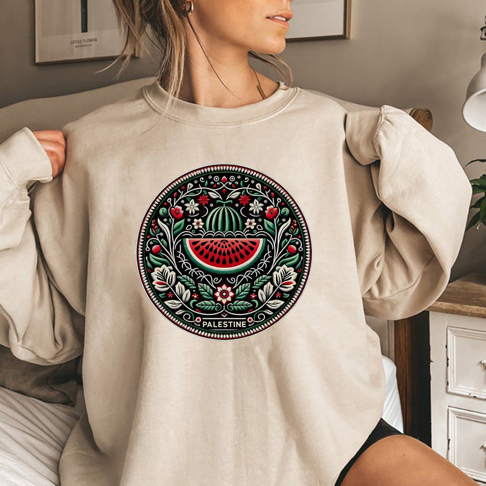 Frau trägt beigen Pullover mit palästinensischem Stickmuster, Wassermelonen-Design. Modetrend, kulturelle Kleidung, gemütlicher Stil.