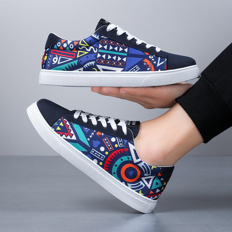 Bunte Sneaker mit geometrischem Muster, weißer Sohle und Schnürsenkeln, gehalten von einer Hand. Modische Freizeitschuhe für Herren.