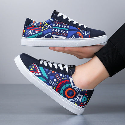 Bunte Sneaker mit geometrischem Muster, weißer Sohle und Schnürsenkeln, gehalten von einer Hand. Modische Freizeitschuhe für Herren.
