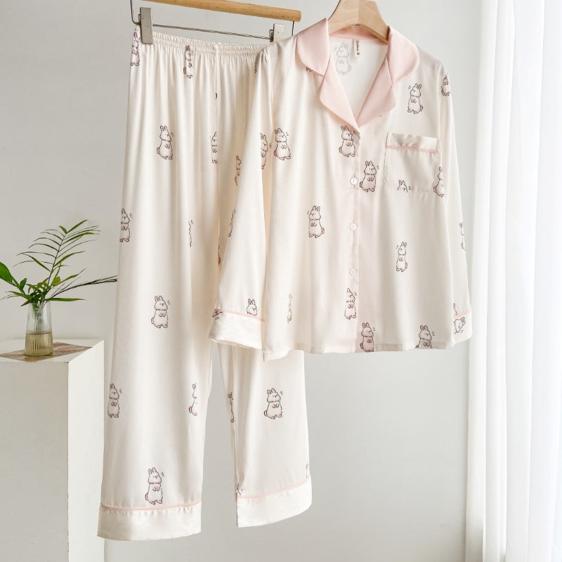 Zweiteiliger Damen-Pyjama mit niedlichem Tiermuster, hängend auf Holzkleiderbügel. Weiches, cremefarbenes Material, ideal für gemütliche Nächte.