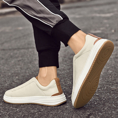 Beige Herren-Sneaker aus Leder mit braunen Akzenten, rutschfeste Gummisohle, getragen auf Asphalt. Bequeme Freizeitschuhe für Männer.