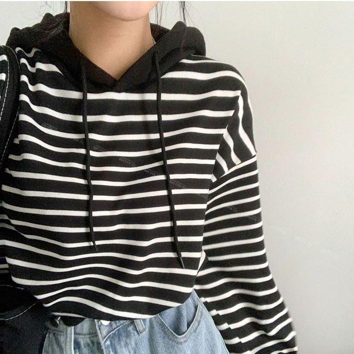 Schwarz-weiß gestreifter Hoodie mit Kapuze, getragen von Person in blauer Jeans. Modetrend, lässiger Stil, Streetwear, bequemes Outfit.