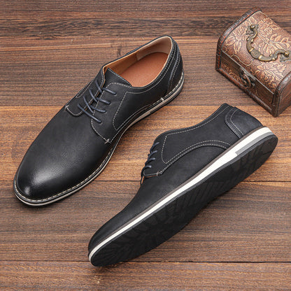 Schwarze Herren-Lederschnürschuhe auf Holzboden, elegante Freizeitschuhe mit weißer Sohle, neben antiker Schmuckschatulle.