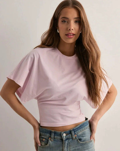 Junge Frau in rosa T-Shirt und blauer Jeans, lächelnd, mit langen braunen Haaren. Mode, Freizeitkleidung, stilvolles Outfit, Porträt.