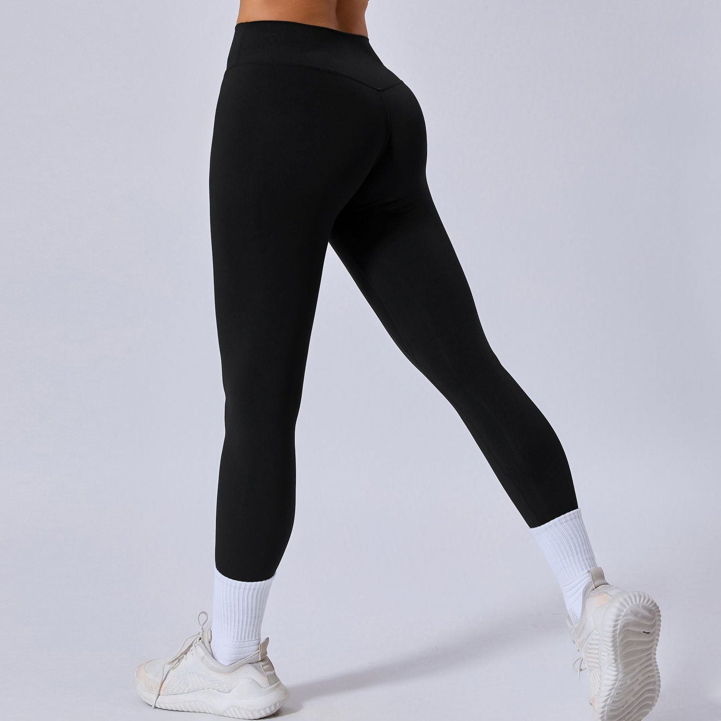 Damen in schwarzen Leggings, weiße Sportschuhe und Socken, Rückansicht. Sportbekleidung, Fitnessmode, bequeme Leggings für Training und Alltag.