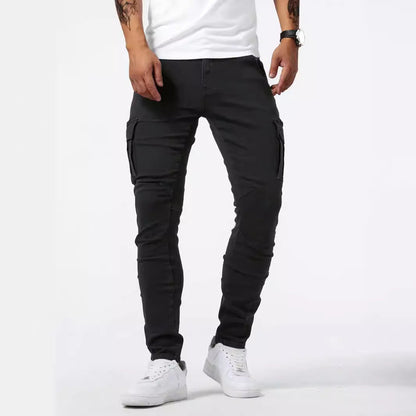 Mann trägt schwarze Cargo-Hose und weiße Sneaker, steht vor weißem Hintergrund. Modische Herrenbekleidung, lässiger Stil, Streetwear-Trend.