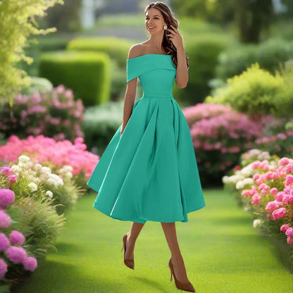 Frau in türkisfarbenem Off-Shoulder-Kleid spaziert durch blühenden Garten mit rosa Blumen, Sommermode, elegantes Outfit, Naturhintergrund.