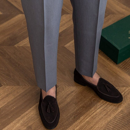 Graue Anzughose und schwarze Slipper auf Holzfußboden, elegante Herrenmode, stilvolle Businesskleidung, hochwertige Materialien.