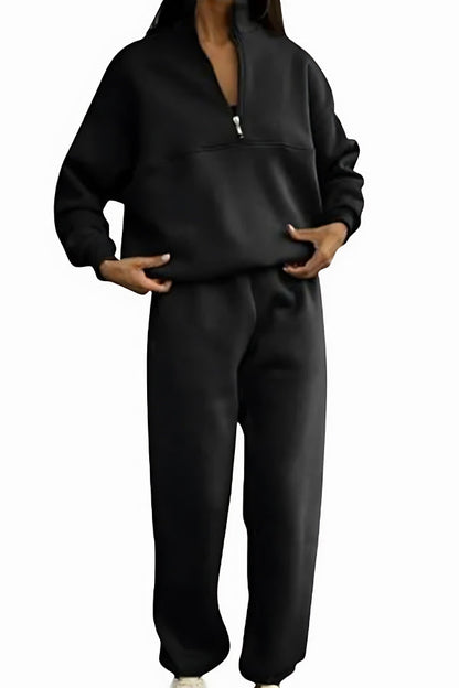 Frau in schwarzem Jogginganzug mit Reißverschluss, lässige Sportbekleidung, gemütlicher Freizeitlook, modischer Zweiteiler für Damen.