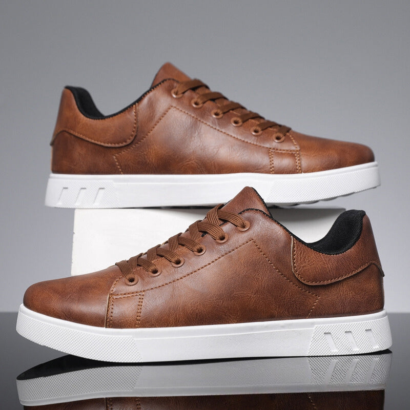 Braune Herrensneaker aus Leder mit weißer Sohle, seitlich aufgestellt. Modische Freizeitschuhe, ideal für Alltag und Freizeit.
