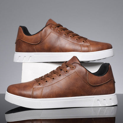Braune Herrensneaker aus Leder mit weißer Sohle, seitlich aufgestellt. Modische Freizeitschuhe, ideal für Alltag und Freizeit.
