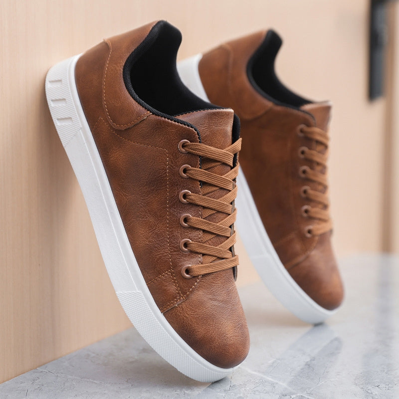 Braune Ledersneaker mit weißer Sohle, seitlich an eine Wand gelehnt. Modische Herrenschuhe, ideal für Freizeit und Alltag.