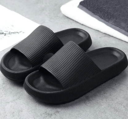 Schwarze Badeschlappen auf grauem Hintergrund, rutschfest und bequem, ideal für Badezimmer oder Strand. Modische und praktische Hausschuhe.