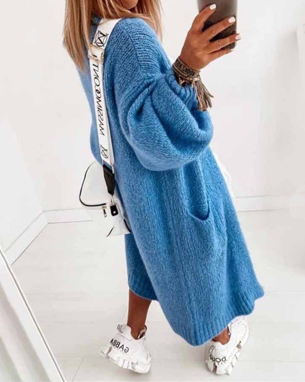 Frau in blauem Strickkleid, weiße Sneakers, weiße Umhängetasche, Selfie im Spiegel, modisches Outfit, lässiger Stil, Herbstmode.