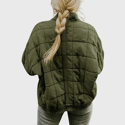 Frau mit geflochtenem Haar trägt eine olivgrüne, gesteppte Jacke. Modetrend, Herbstmode, Damenbekleidung, Outdoorjacke.