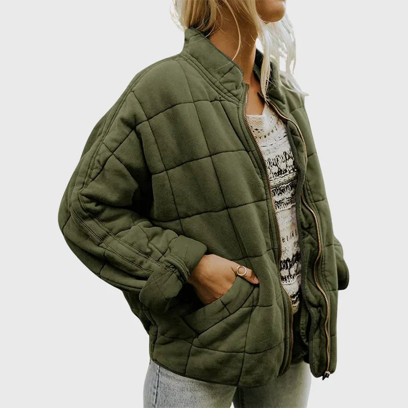 Frau in olivgrüner Steppjacke, lässig offen getragen, mit gemustertem Oberteil und Jeans. Modetrend, Herbstmode, Damenjacke, Streetstyle.