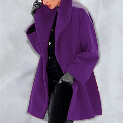 Frau in lila Oversize-Mantel, schwarzer Kleidung und grauen Handschuhen. Modetrend, Herbstmode, stilvoller Look, eleganter Mantel.