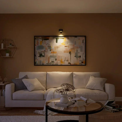 Gemütliches Wohnzimmer mit beigem Sofa, abstraktem Gemälde an der Wand, stilvoller Beleuchtung und modernem Couchtisch. Elegantes Interieur-Design.