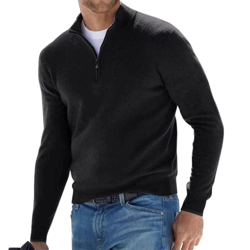 Mann in schwarzem Pullover mit Reißverschluss und blauer Jeans. Modischer Herrenpullover, lässiger Stil, ideal für Herbst und Winter.