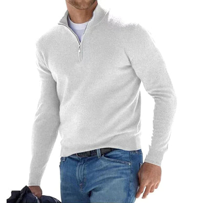 Mann in weißem Pullover mit Reißverschluss und blauer Jeans, hält eine Jacke. Modischer Herren-Look, Freizeitkleidung, stilvoll und bequem.
