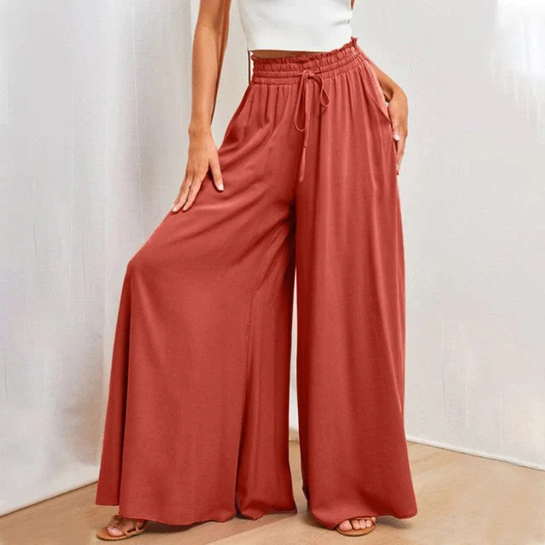 Frau trägt weite, rote Palazzo-Hose mit elastischem Bund und Kordelzug. Modetrend, Damenbekleidung, bequeme Sommerhose, eleganter Stil.