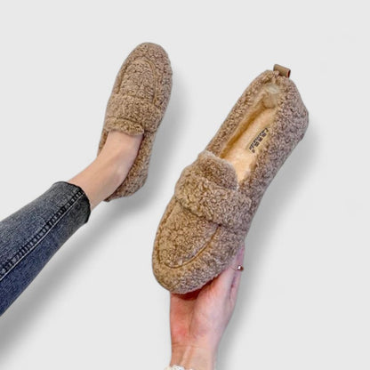 Braune, flauschige Damen-Loafer aus Kunstpelz, getragen mit blauen Jeans. Bequeme, modische Schuhe für Herbst und Winter.