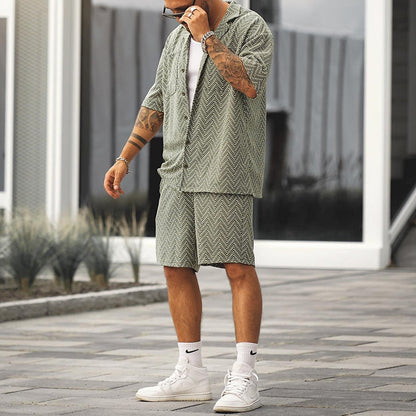Mann in grünem Sommeranzug mit geometrischem Muster, weißen Sneakers und Socken. Trendige Herrenmode, lässiger Stil, urbaner Hintergrund.