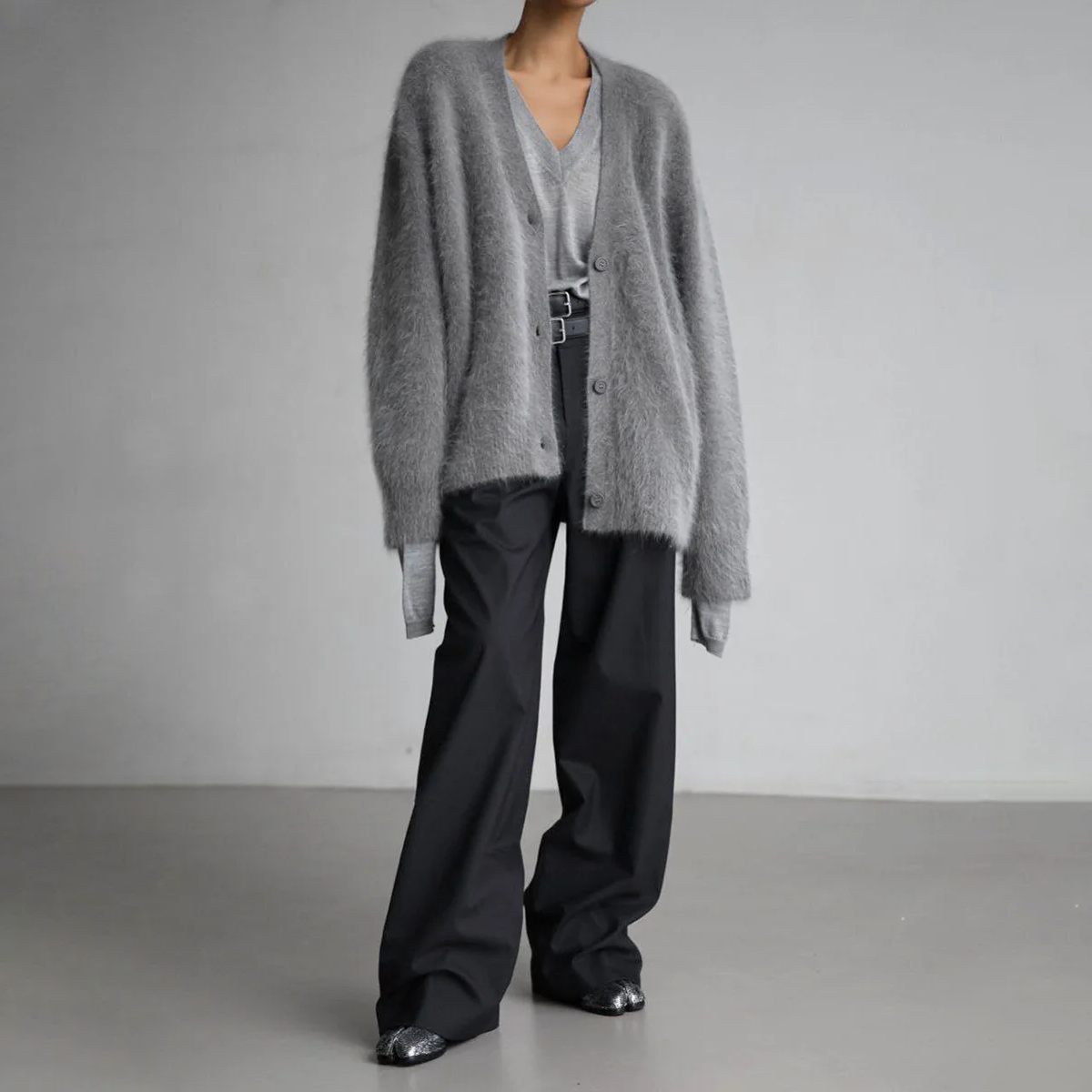 Grauer Oversize-Cardigan und schwarze weite Hose, modisches Outfit für Herbst/Winter. Eleganter, minimalistischer Stil, ideal für kühle Tage.