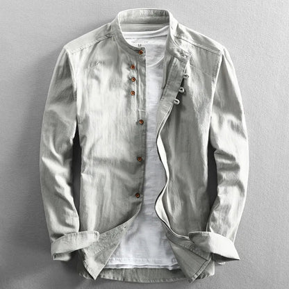 Hellgraue Herrenjacke mit Stehkragen und braunen Knöpfen, über einem weißen T-Shirt. Modische, lässige Oberbekleidung für Männer.