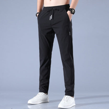 Schwarze Herren-Sporthose, lässig, mit Kordelzug, kombiniert mit weißen Sneakers. Ideal für Fitness, Freizeit und Sportbekleidung.