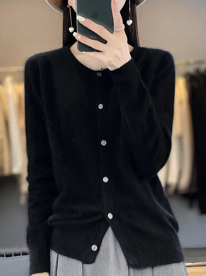 Frau in schwarzem Strickcardigan mit Knöpfen, hält Smartphone, trägt grauen Rock. Modetrends, Damenmode, eleganter Look, Herbstkleidung.