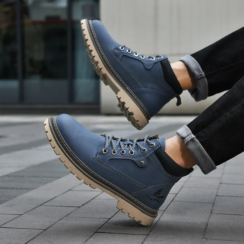 Blaue Herren-Wanderschuhe mit robusten Sohlen, getragen von einer Person in schwarzer Jeans. Outdoor-Schuhe, ideal für Trekking und Freizeit.