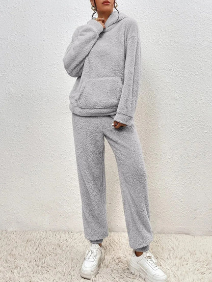 Grauer Fleece-Hoodie und Jogginghose Set, gemütliche Damen-Loungewear, weiches Material, modisch, ideal für Herbst und Winter, kombiniert mit weißen Sneakers.