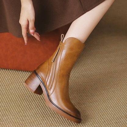 Damenstiefel aus braunem Leder mit Blockabsatz und Reißverschluss, stilvoll und modern, auf beigem Teppich. Perfekt für Herbstmode.