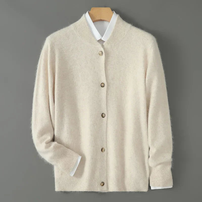 Beige Strickjacke aus Kaschmir mit Knopfleiste, hängend auf Holzkleiderbügel vor grauem Hintergrund. Elegante, warme Damenmode.
