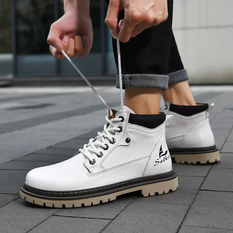 Weiße Herrenstiefel mit Schnürsenkeln, robustem Profil und schwarzem Kragen, getragen auf grauem Pflaster. Ideal für Outdoor und urbanen Stil.