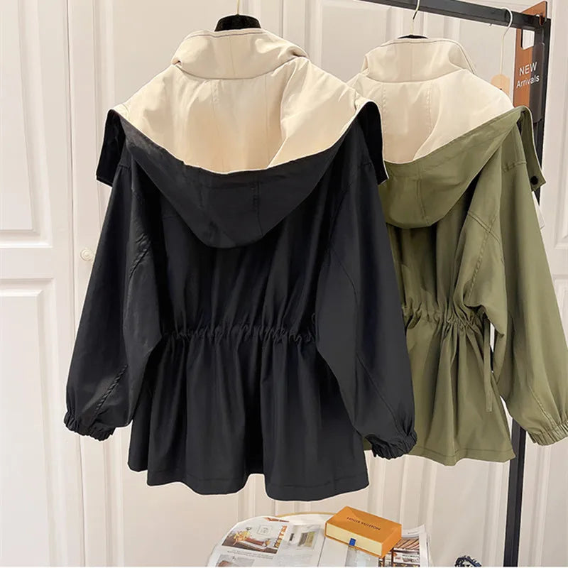 Zwei Damenjacken mit Kapuze, eine in Schwarz und eine in Olivgrün, auf Kleiderbügeln. Modetrend Herbst, stilvolle Outdoor-Bekleidung.