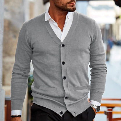 Eleganter Mann in grauem Cardigan und weißem Hemd, modischer Look, urbane Umgebung, stilvolle Herrenmode, zeitloser Stil, moderne Eleganz.
