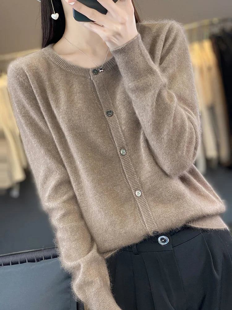 Frau in braunem Strickcardigan mit Knöpfen, hält Smartphone. Modetrend Herbst, elegante Damenbekleidung, gemütlicher Look.