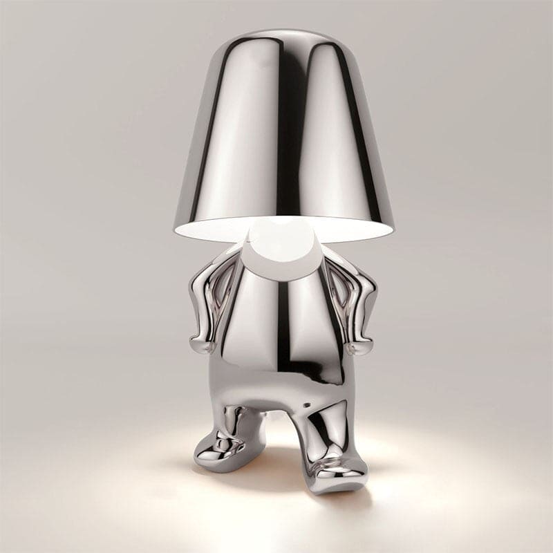Silberne Designer-Tischlampe in Form einer stilisierten Figur, modernes Interieur, einzigartiges Beleuchtungsdesign, glänzende Metalloberfläche.