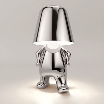 Silberne Designer-Tischlampe in Form einer stilisierten Figur, modernes Interieur, einzigartiges Beleuchtungsdesign, glänzende Metalloberfläche.