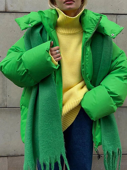 Frau in grüner Daunenjacke und gelbem Rollkragenpullover, kombiniert mit grünem Schal und blauer Jeans. Wintermode, Streetstyle, trendige Outfits.
