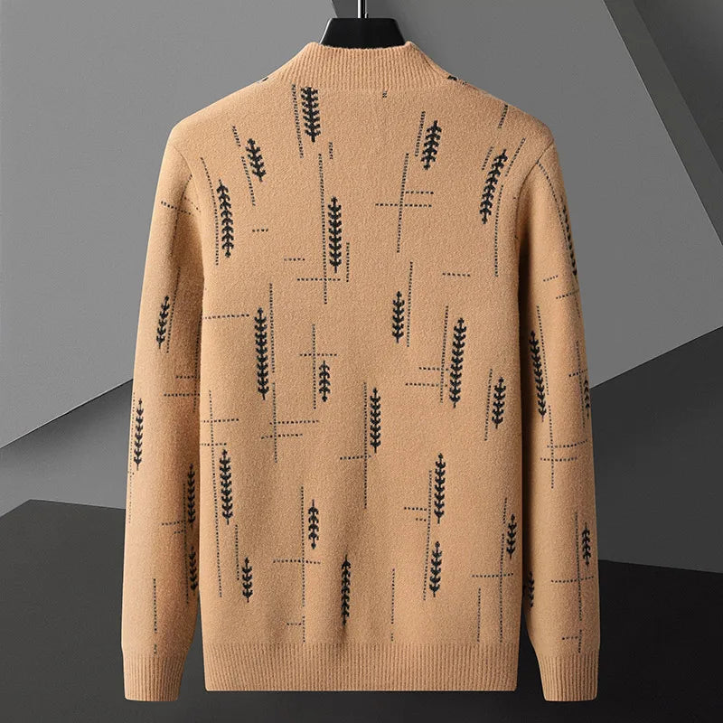 Beiger Pullover mit schwarzem Blattmuster, geometrischem Design, hängend auf einem Kleiderbügel vor grauem Hintergrund. Modischer Strickpullover.