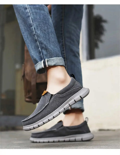 Graue Herren-Sneaker aus Stoff, kombiniert mit blauen Jeans. Bequeme, rutschfeste Freizeitschuhe für den Alltag. Ideal für stilvolle Freizeitoutfits.