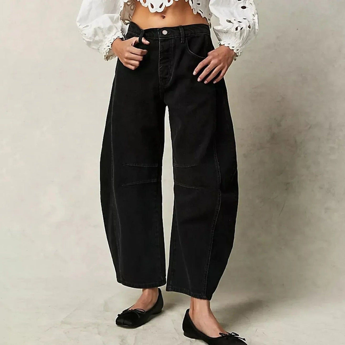 Frau trägt schwarze, weite Jeans und weiße, bestickte Bluse. Modetrend, Damenmode, lässiger Stil, bequeme Kleidung, Streetwear-Look.