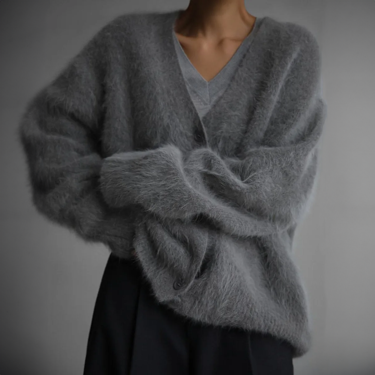 Grauer, flauschiger Cardigan aus Mohair, getragen von einer Person. Modischer, gemütlicher Strickpullover für Herbst und Winter.