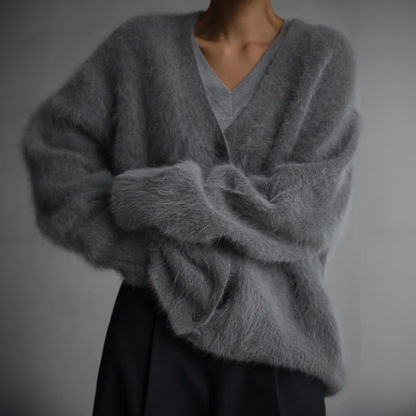 Grauer, flauschiger Cardigan aus Mohair, getragen von einer Person. Modischer, gemütlicher Strickpullover für Herbst und Winter.