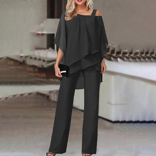 Elegante Frau in schwarzem, schulterfreiem Hosenanzug mit Clutch, stehend in modernem Innenraum. Modetrend, Damenbekleidung, Abendmode.